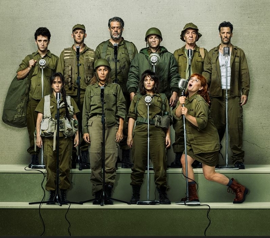 תמונת מופע: תמונה של כל שחקני ההצגה במדים של צהל עומדים ולפניהם מקרופונים