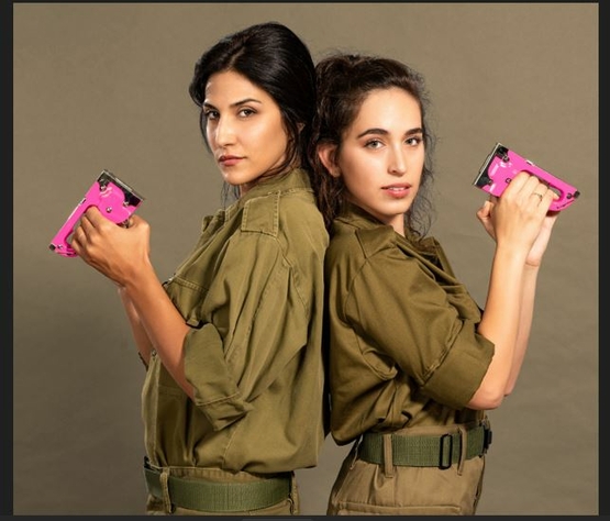 תמונת מופע: תמונה של מגי אזרזר ומשי קלינשטיין במדי צהל עומדות גב אל גב מחזיקות אקדח סיכות