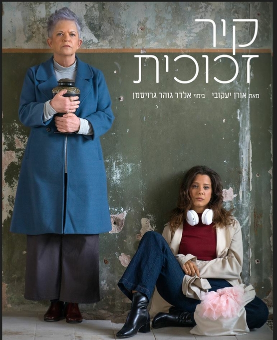 תמונת מופע: אישה יושבת על הרצפה עם אוזניות על הכתפיים ולידה אישה מבוגרת עם שיער קצר עומדת ומחזיקה כד אפר