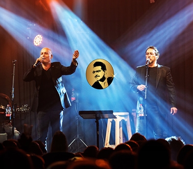 תמונת מופע: תמונה של גוסטו וליאור אלמליח עומדים על הבמה ושרים&period; ברקע גרפיקה של ג'ו עמר