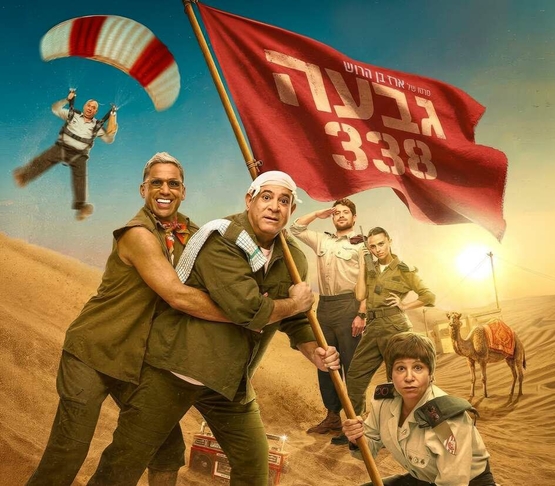 תמונת מופע: תמונה של משתתפי הסרט אוחזים בדגל גדול וברקע צנחן